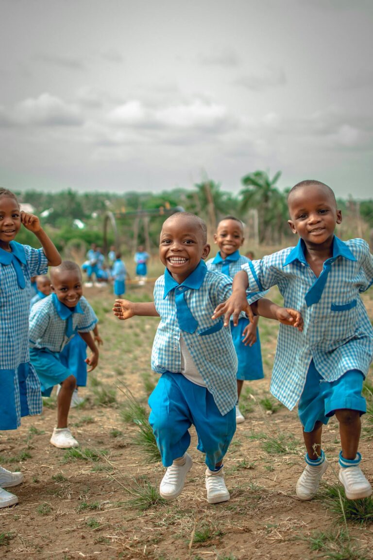 Joyful group of African school children running and playing outside in uniforms.